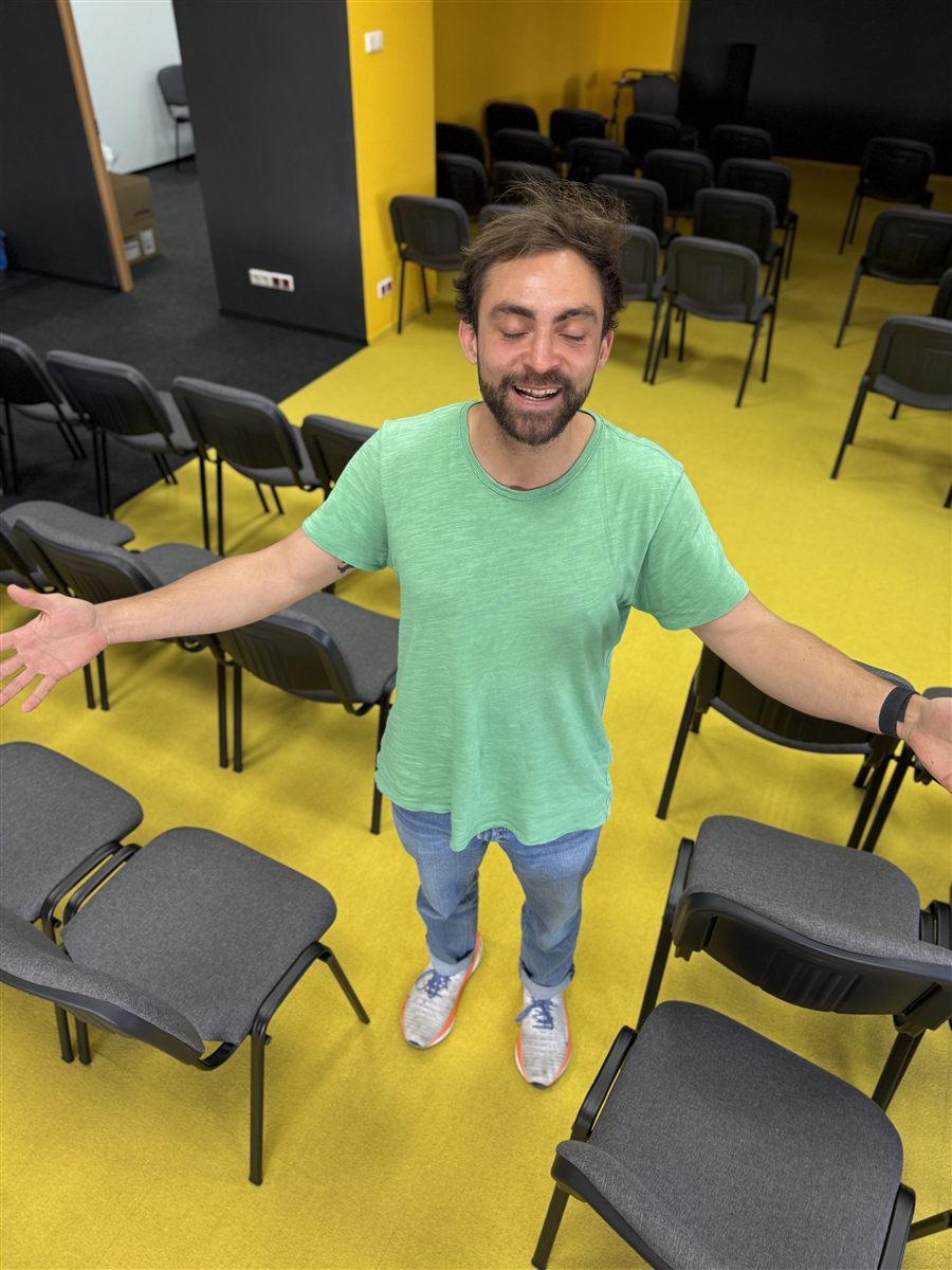 Tinu Bosînceanu standing arms open in an Upgrade Education classroom